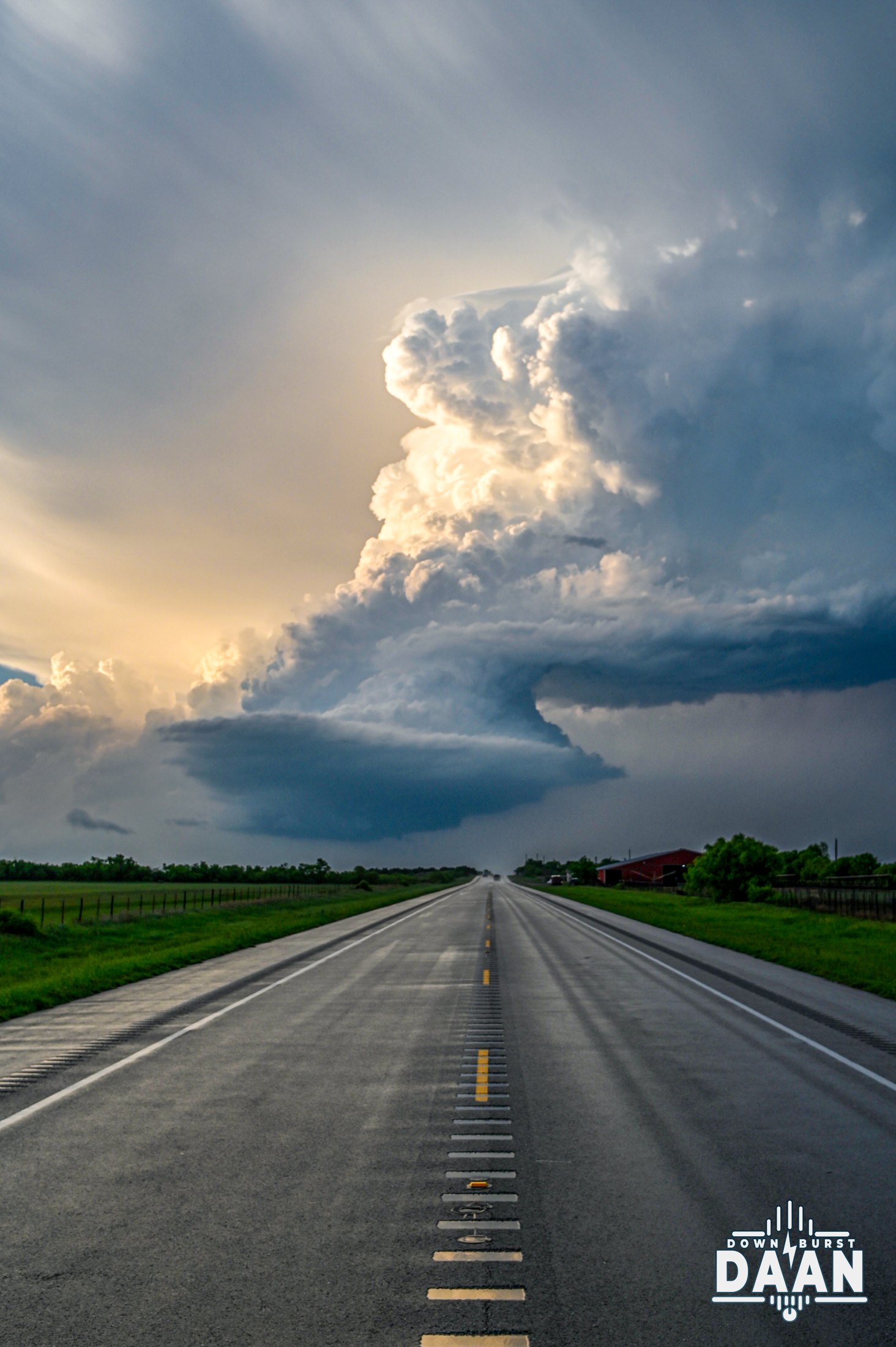 Towering storm cloud at the end of a long, straight Plains highway
