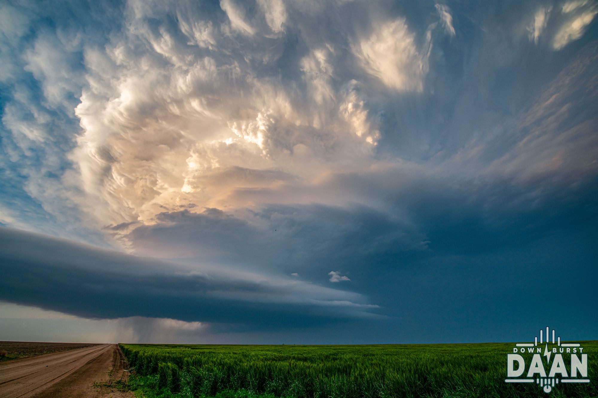 Mammatus clouds spreading over a green farm field after a severe storm
